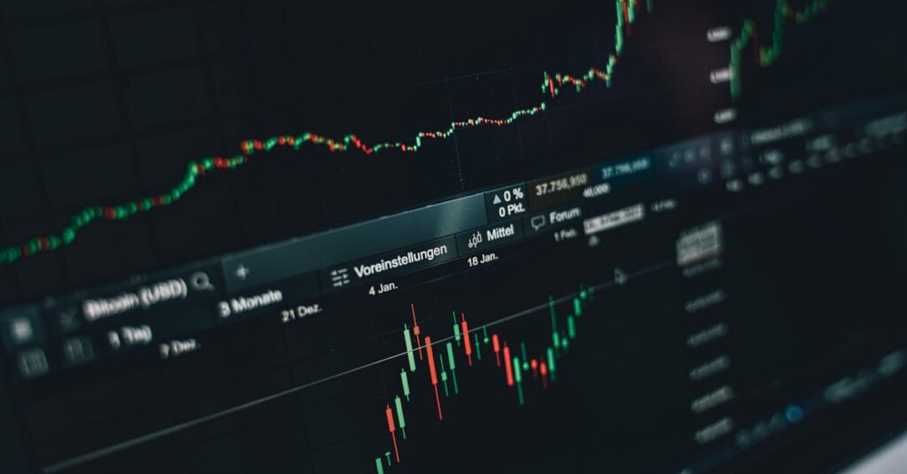 中古サックスの買取価格を確認する男性の後ろ姿。机には楽器と書類が並ぶ。